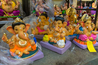 A collection of brass Ganesha idols in various sizes displayed on a rustic table.