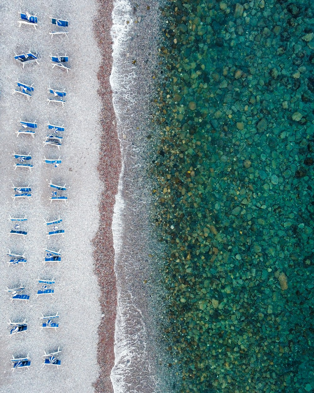 an aerial view of a beach with chairs and a body of water