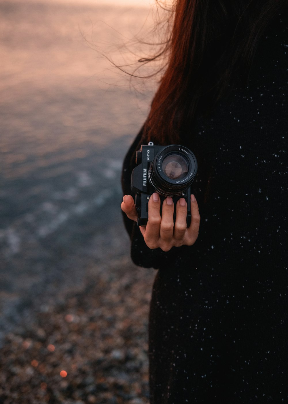 a woman holding a camera on a beach