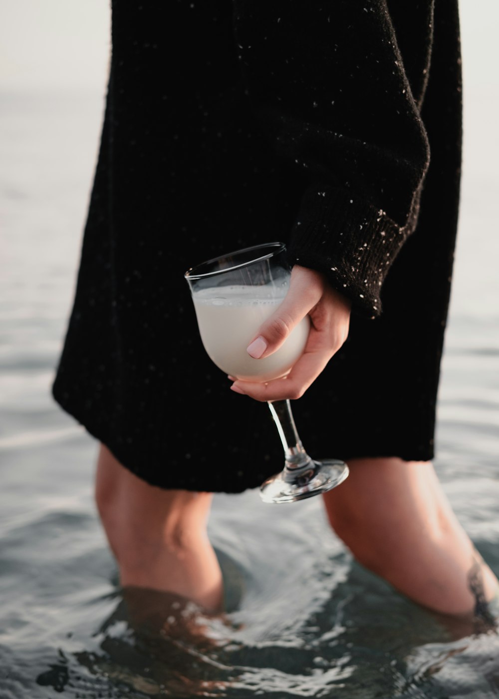 a person holding a wine glass in the water