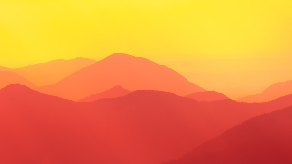 um céu amarelo e vermelho com montanhas no fundo