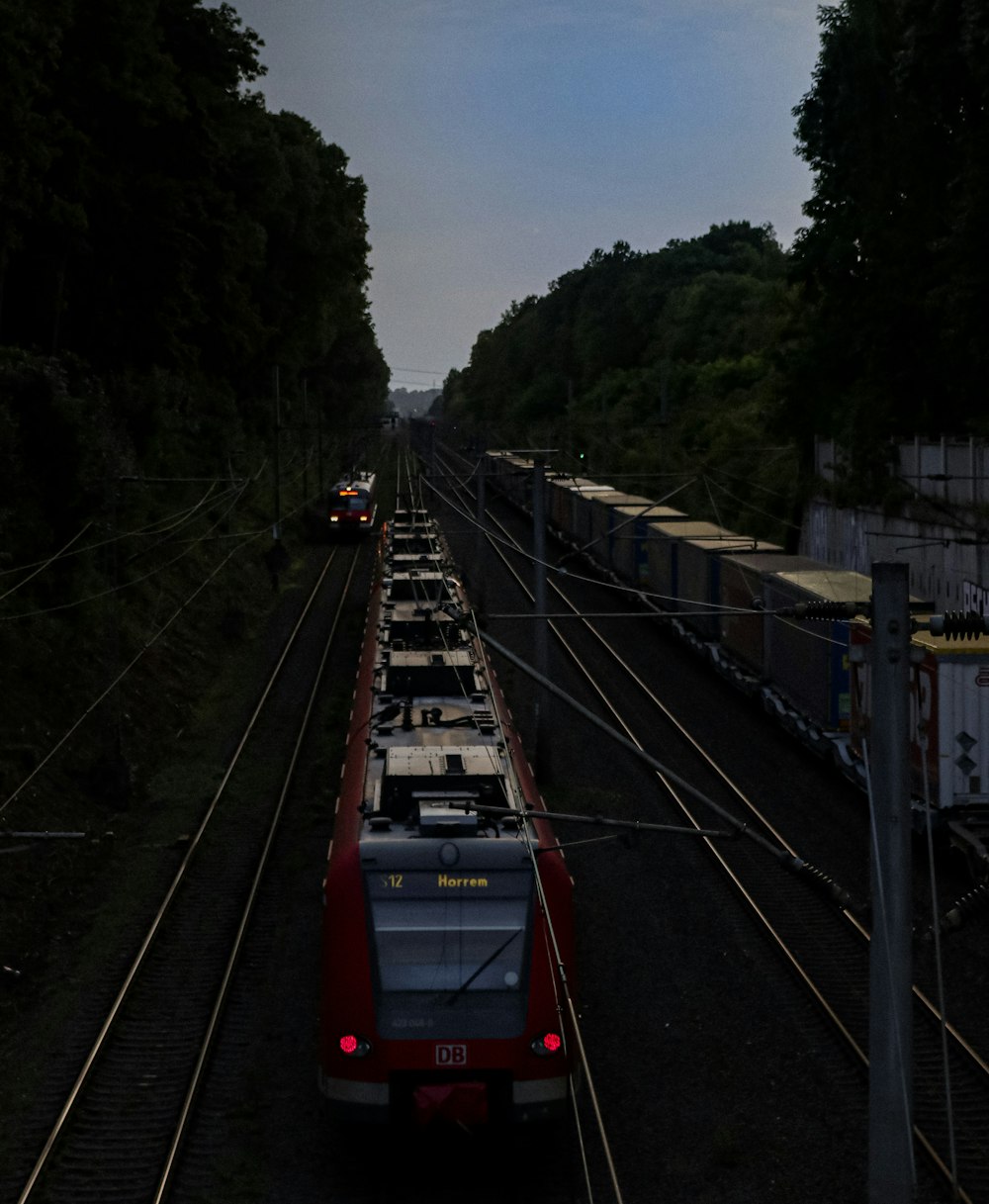 a red train traveling down train tracks next to a forest