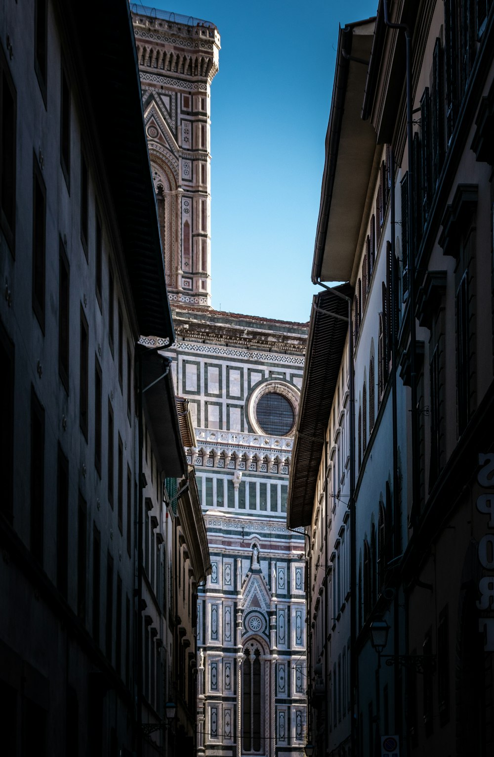 a narrow alley way with a clock tower in the background