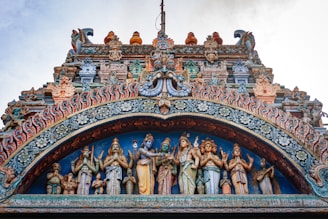 An ancient temple facade adorned with colorful flowers and intricate carvings at a tirth site.