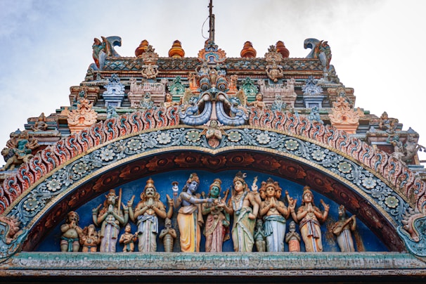 An ancient temple facade adorned with colorful flowers and intricate carvings at a tirth site.