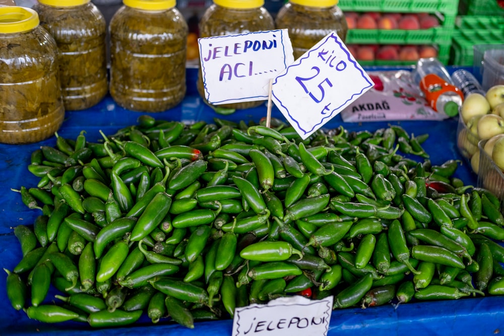 a pile of green peppers sitting on top of a blue table