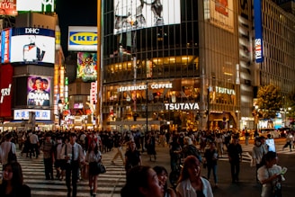 A vibrant street scene in Shibuya crossing filled with colorful lights and bustling crowds at night.