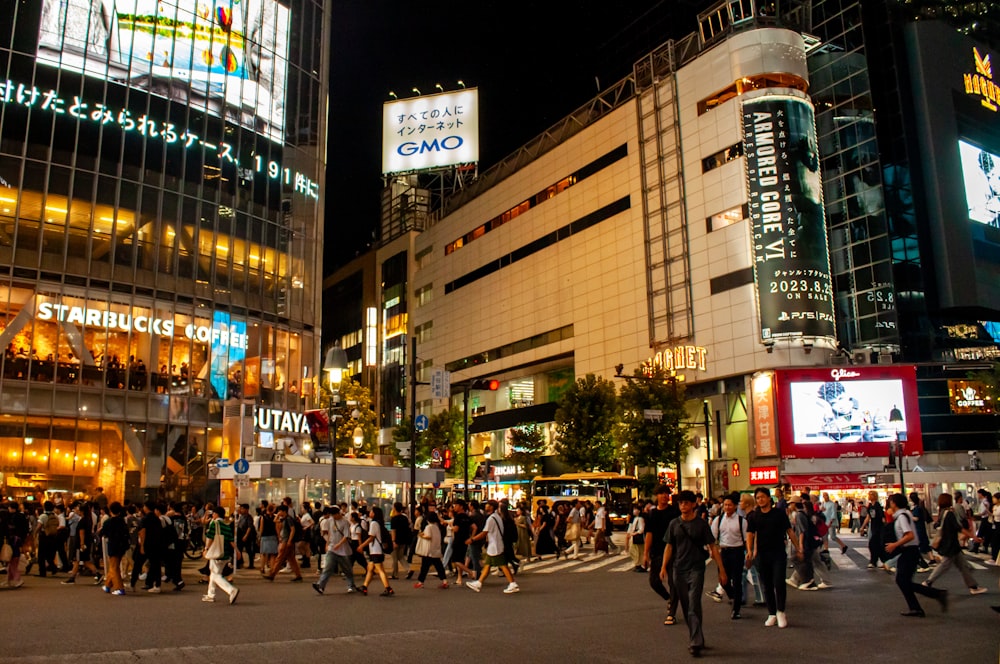 a crowd of people crossing a street at night