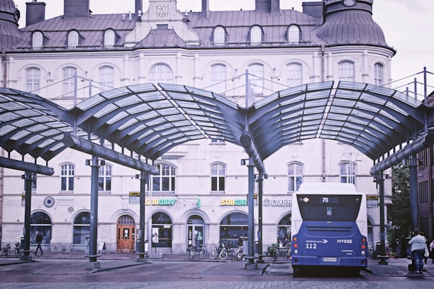A modern bus parked at a city terminal with passengers boarding.