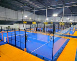 A group of enthusiastic padel players celebrating a winning point on a sleek black court.