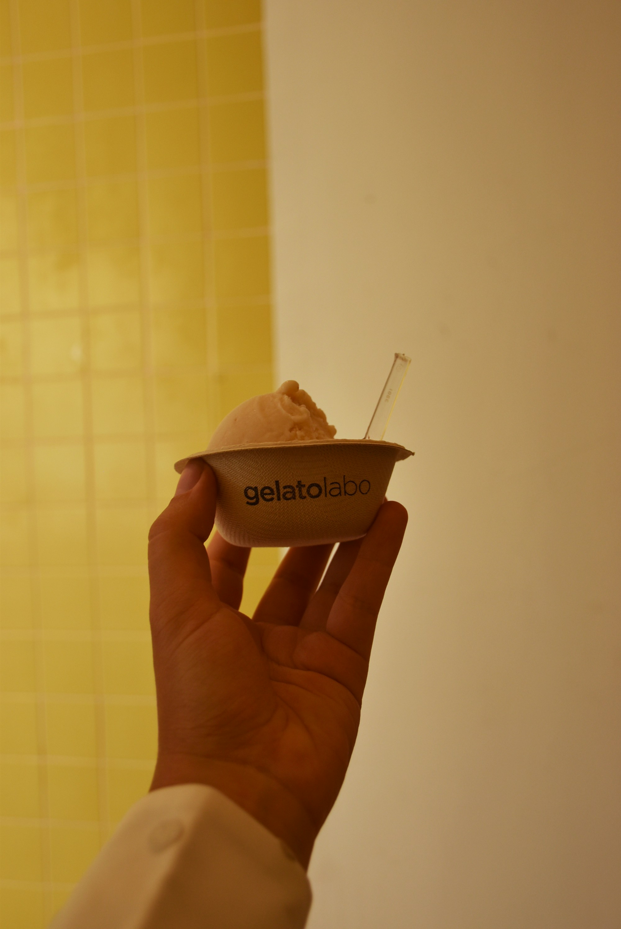 A person holding up a cupcake with a bite taken out of it