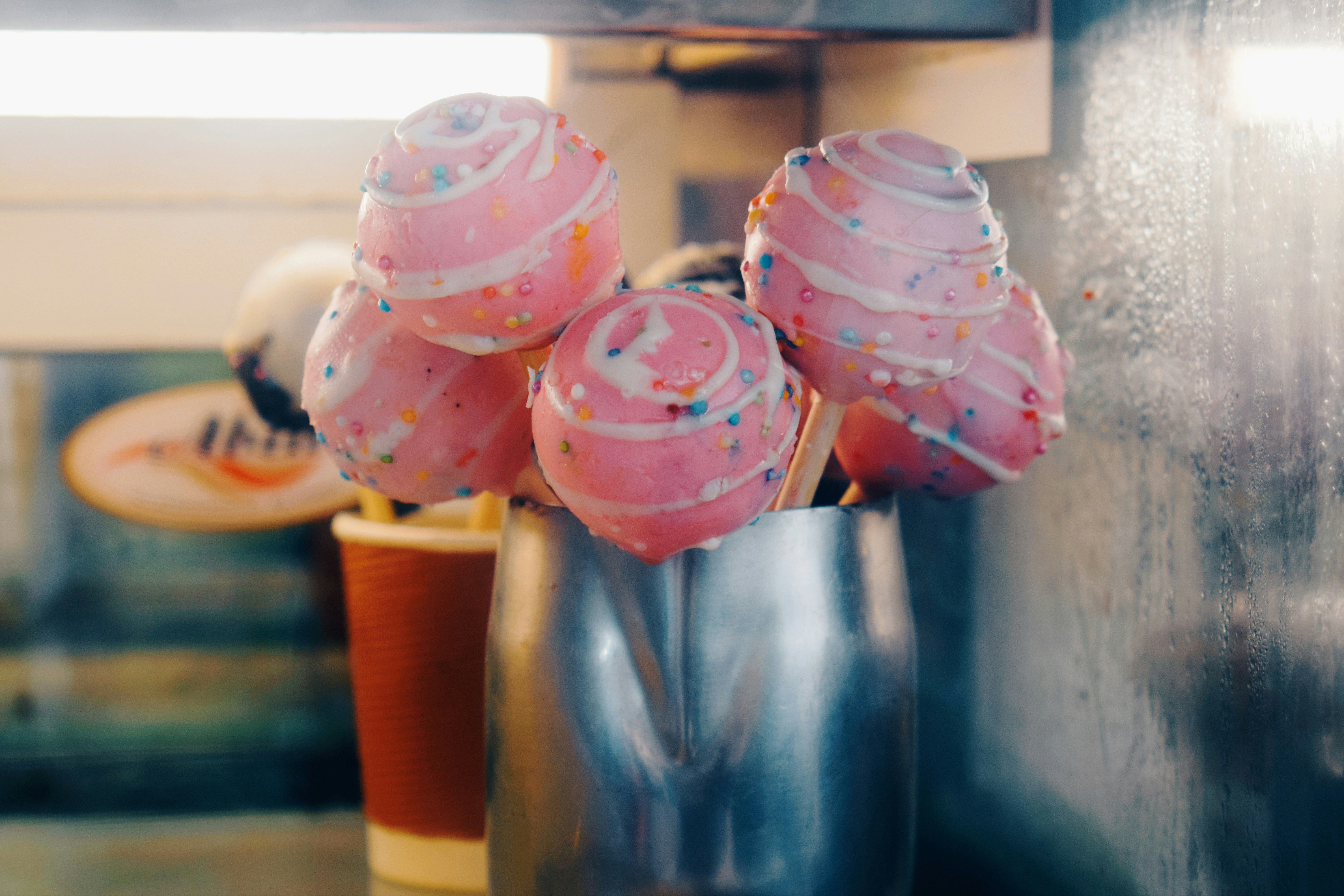 a group of pink frosted donuts sitting on top of a metal cup