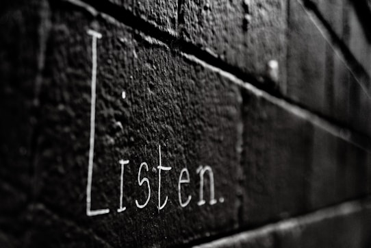 a black and white photo of the word listen written on a brick wall