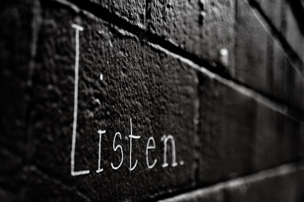 a black and white photo of the word listen written on a brick wall