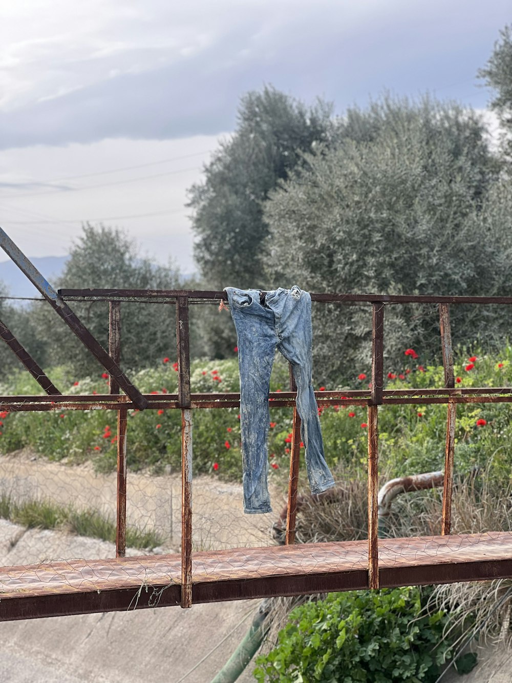 a pair of jeans hanging on a rusty rail