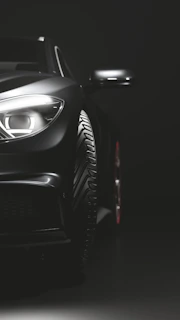 Sleek black luxury car illuminated by cinematic lighting against a dark background
