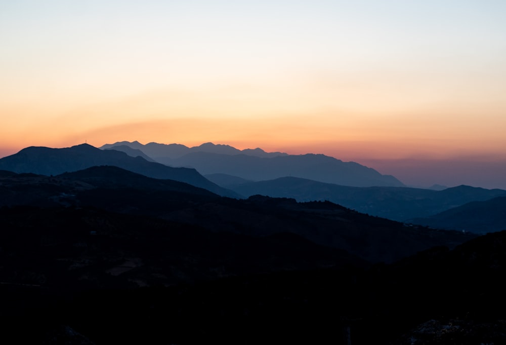 the sun is setting over a mountain range