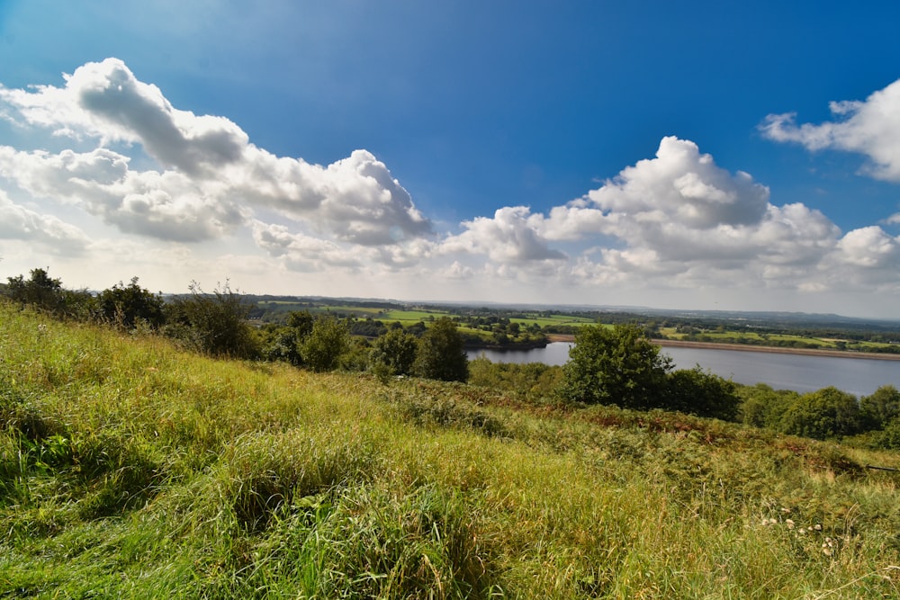 a grassy hill with a lake in the distance