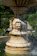 Close-up of a handcrafted cement garden fountain with water flowing gently.