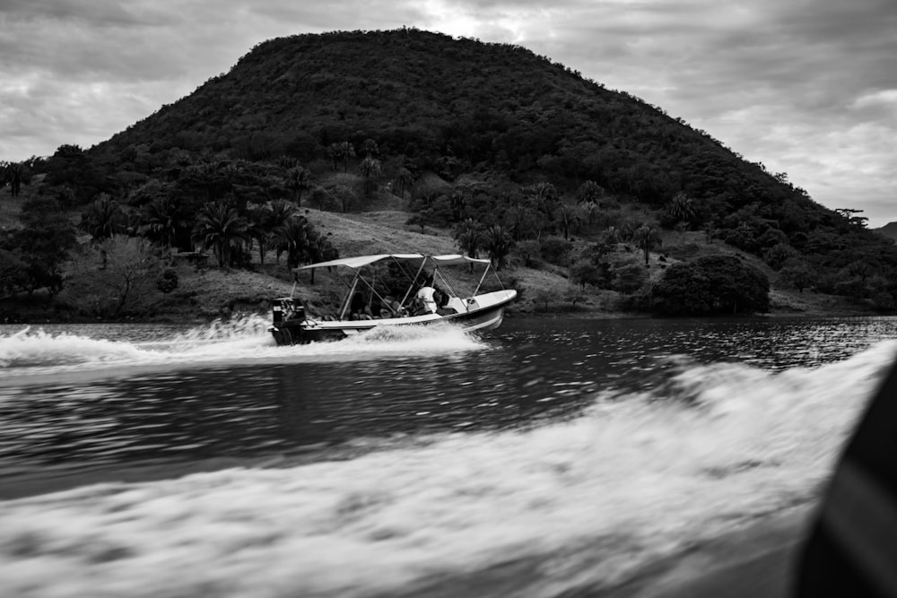 a boat traveling down a river next to a lush green hillside