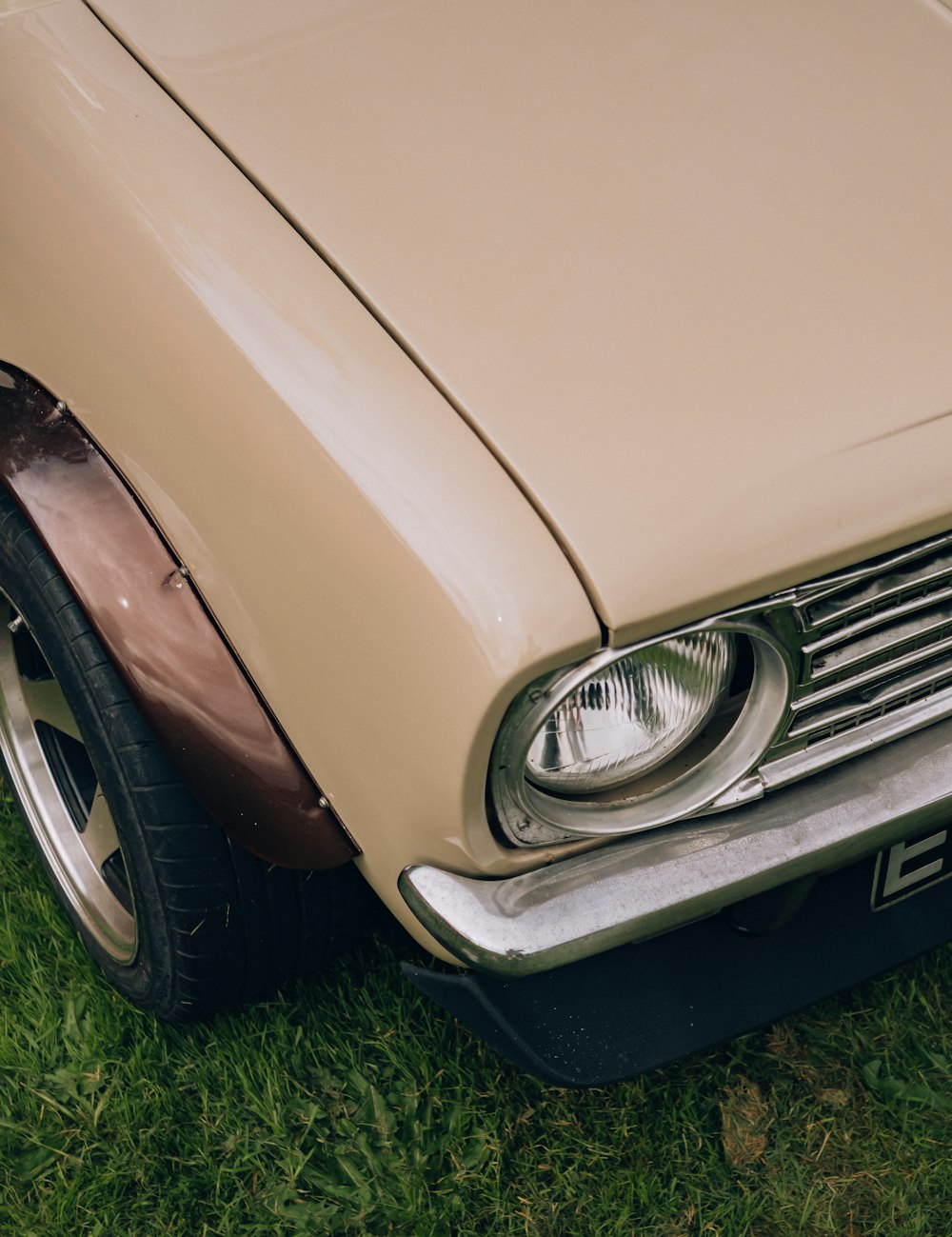 the front end of an old car parked in the grass