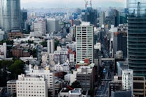 A bustling urban cityscape featuring numerous skyscrapers, residential buildings, and busy streets. The skyline is dense with a variety of architectural styles, and the scene conveys a sense of vibrant city life.