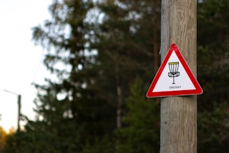 a red and white sign on a wooden pole