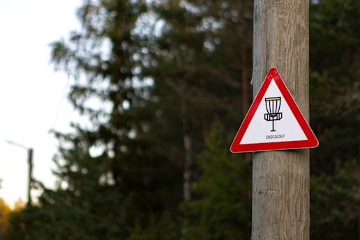 a red and white sign on a wooden pole