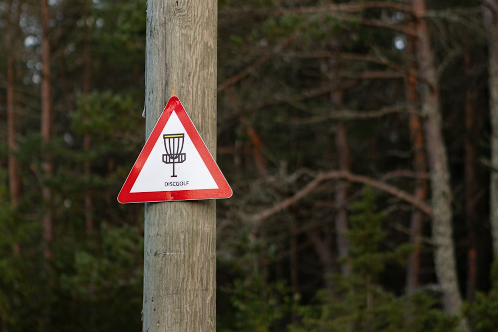 a red and white sign on a wooden pole