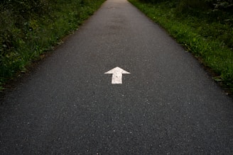 a white arrow painted on a paved road