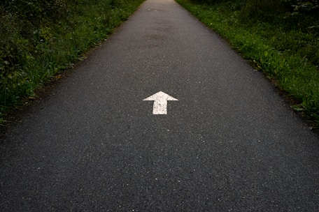 a white arrow painted on a paved road