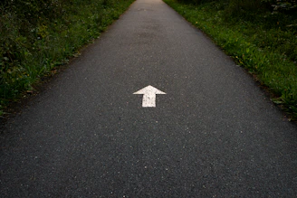 a white arrow painted on a paved road