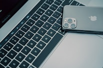 Close-up of hands typing on a MacBook keyboard highlighting the Apple logo.