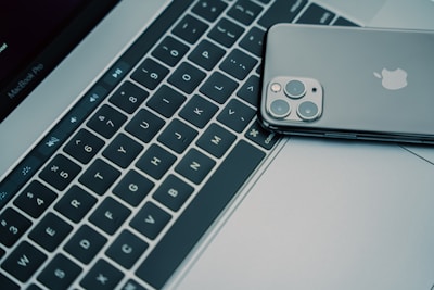 Close-up of hands typing on a MacBook keyboard highlighting the Apple logo.