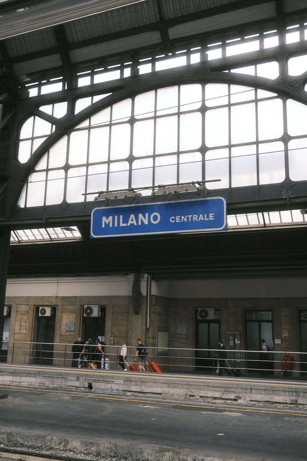 a train station with a blue sign hanging from the ceiling