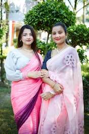 two women standing next to each other in a park