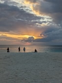 Friends watching a vibrant sunset together on a quiet beach, deep in conversation.