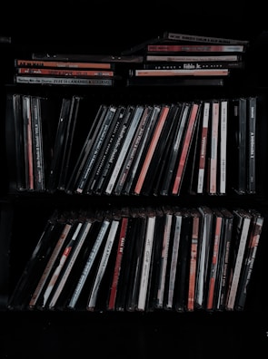 Stacks of solfeggio frequency music albums displayed on a wooden shelf.
