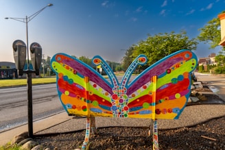 Close-up of a rustic metal garden stake shaped like a butterfly catching sunlight.