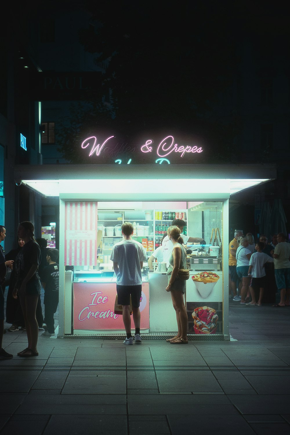 a couple of people standing outside of a food stand