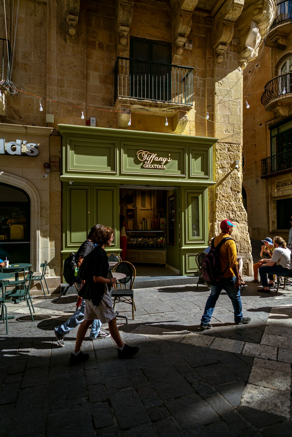 a group of people walking down a street next to a tall building