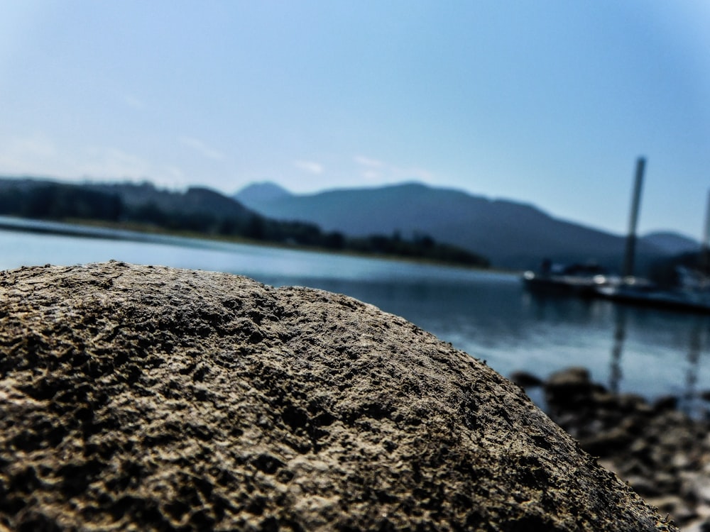 a rock sitting on top of a beach next to a body of water