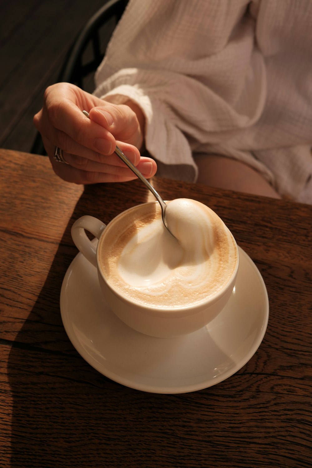a person holding a spoon in a cup of coffee