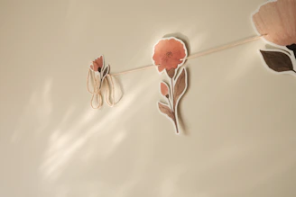 Dusty rose crochet flower garland hanging on a cream wall.