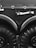 A close-up view of a large vehicle's wheels and bodywork, featuring thick black tires with deep treads. Above the wheels, there is a matte black surface with metal fasteners and a white-handled tool, possibly an axe, mounted horizontally.