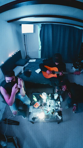 A small group gathered around a singer-songwriter in a sunlit, wood-paneled room.