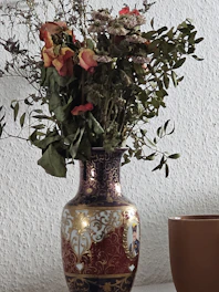 A vintage-style vase with intricate patterns sitting on a rustic shelf.