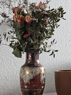 A vintage-style vase with intricate patterns sitting on a rustic shelf.