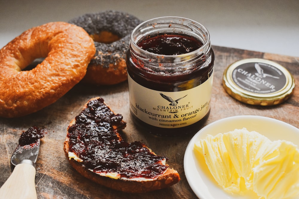 a wooden cutting board topped with a sandwich and jelly