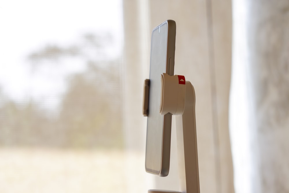 a cell phone is attached to a stand in front of a window